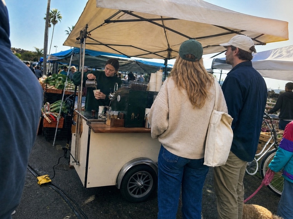 A barista serving coffee at a neighborhood market