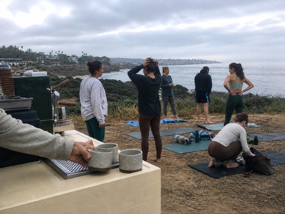 A mobile coffee cart beside a coastal wellness gathering